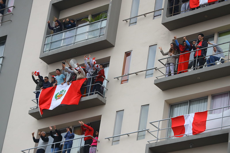 peruanos colocando bbandera del perú en su balcón