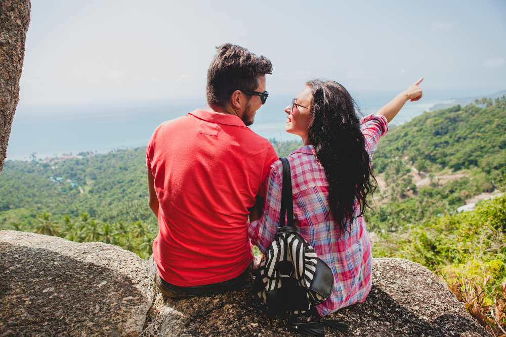 un chico con su novia sentados, apreciando la linda vista del paísaje